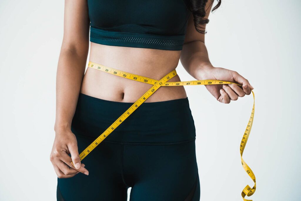 A woman in exercise clothing with a tape measure around her waist