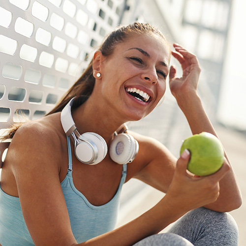 Young woman with headphones eating an apple