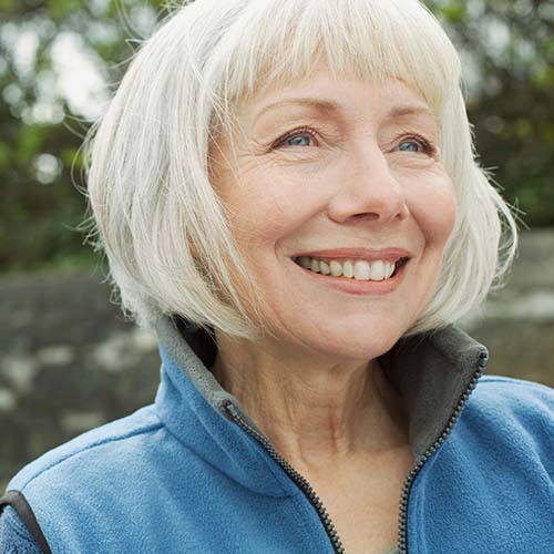 Older woman smiling in a blue vest