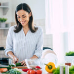 Happy woman cutting vegetables in the kitchen