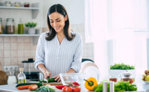 Happy woman cutting vegetables in the kitchen